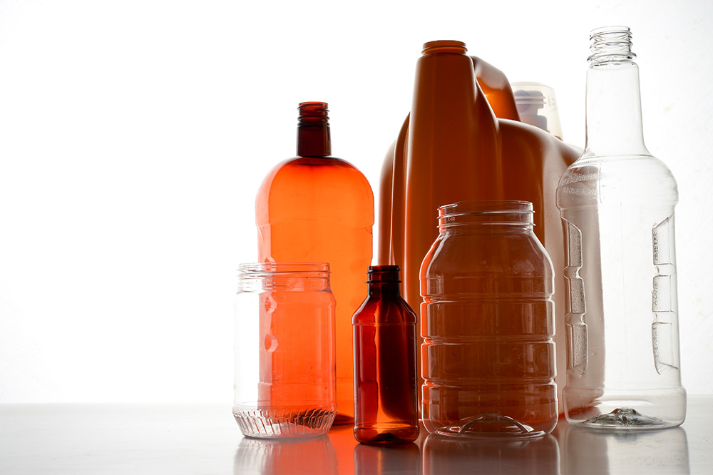 A grouping of different colored plastic bottles sitting on a table with a light background