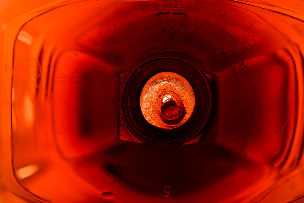 An image of the underside of a red bottle with a hole leak